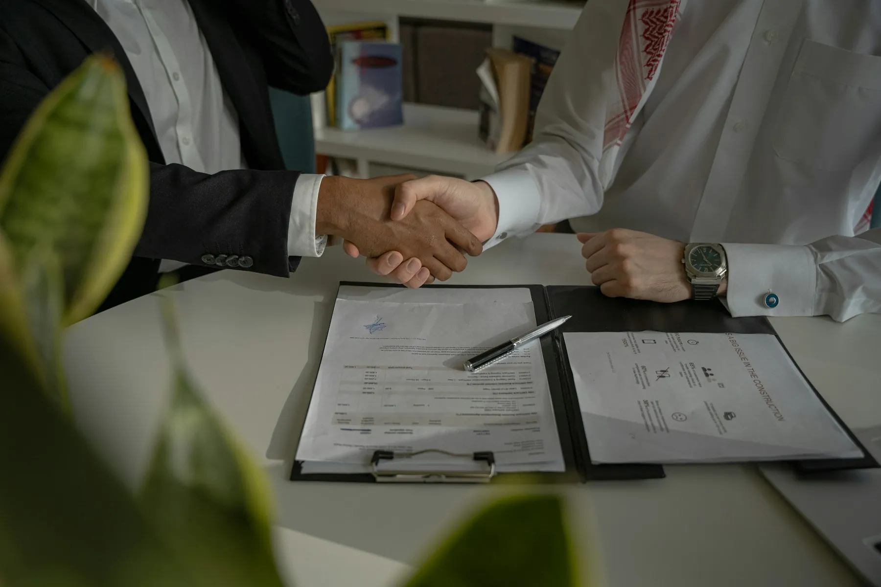 Two people shaking hands over a paper agreement